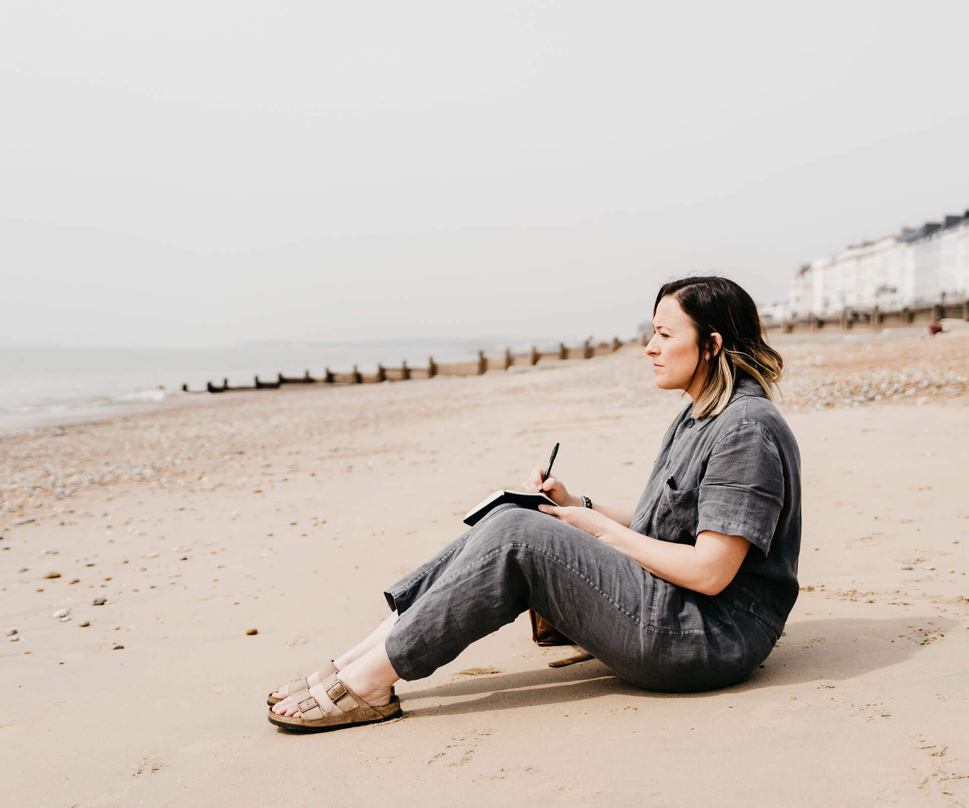 Kiera Chapman sitting on the sand contemplating the sea.